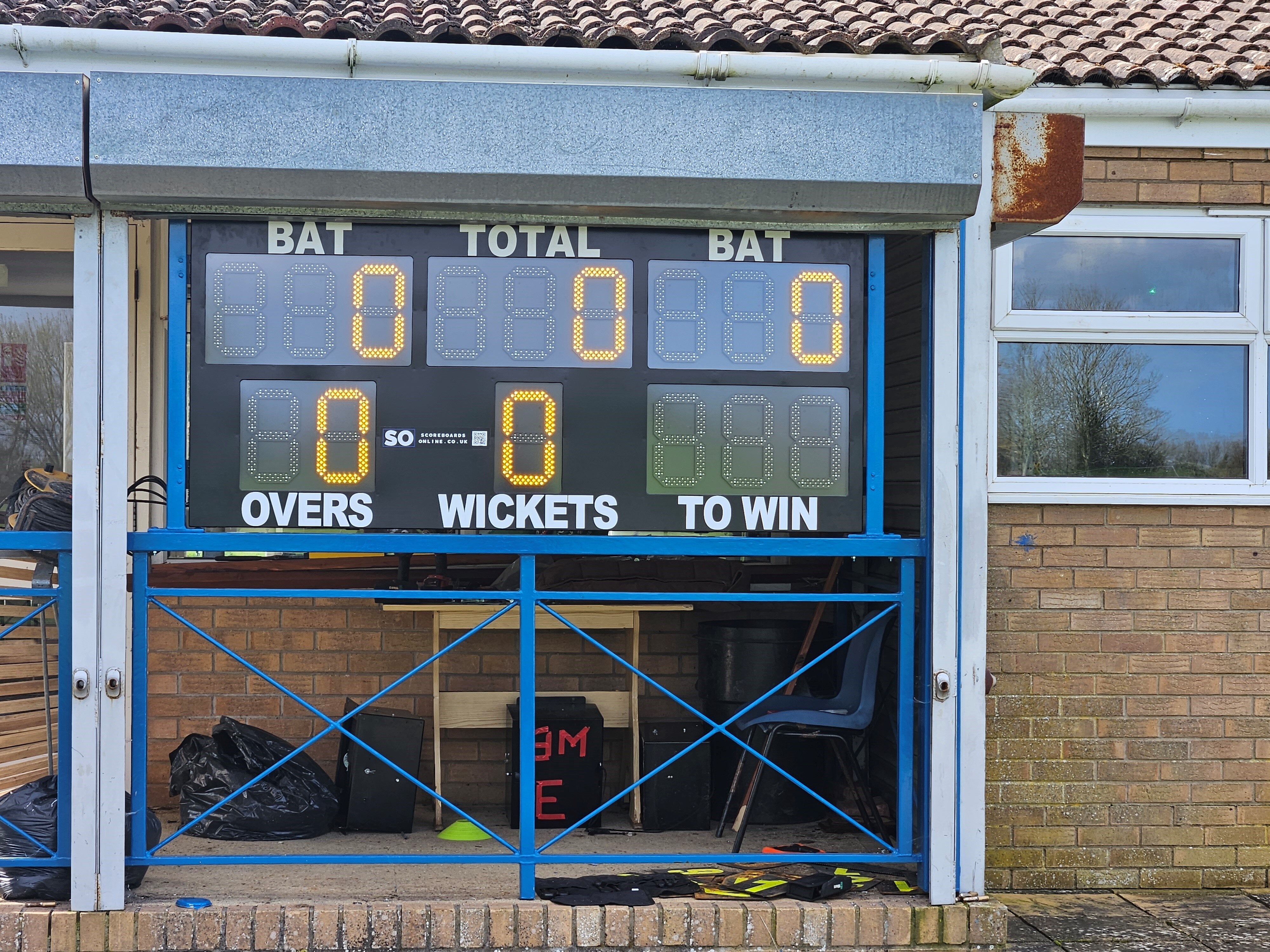 high-visibility LED cricket scoreboard with 16 digits. This electronic scoreboard includes batter names, total, batter strike indicators, overs, a ball number, wickets and 1st Innings.