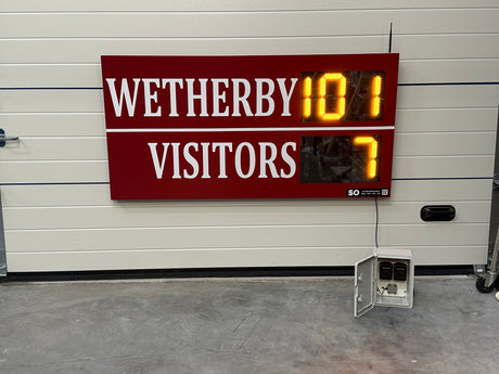 Digital LED scoreboard displaying 'Wetherby 101 Visitors 7' against a white wall. Personalised to include the club's colours.
